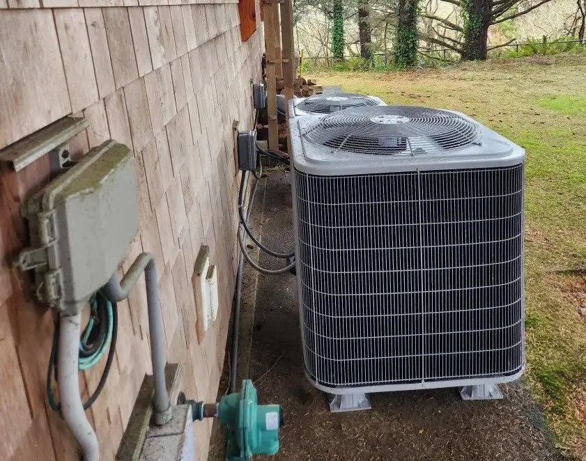 HVAC heat pump units installed beside a coastal Bandon home for year-round heating and cooling comfort.